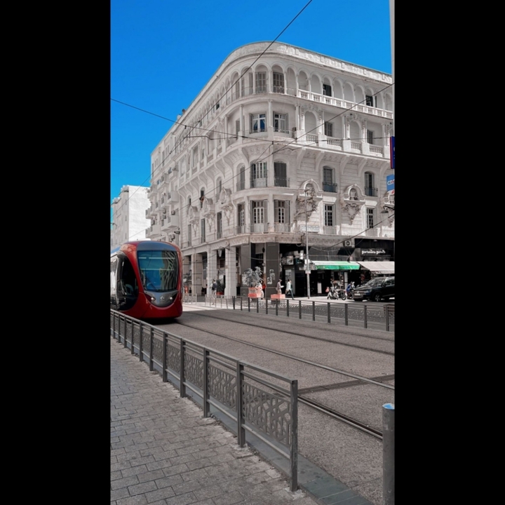 Tramway rouge circulant dans une ville à l'architecture historique.