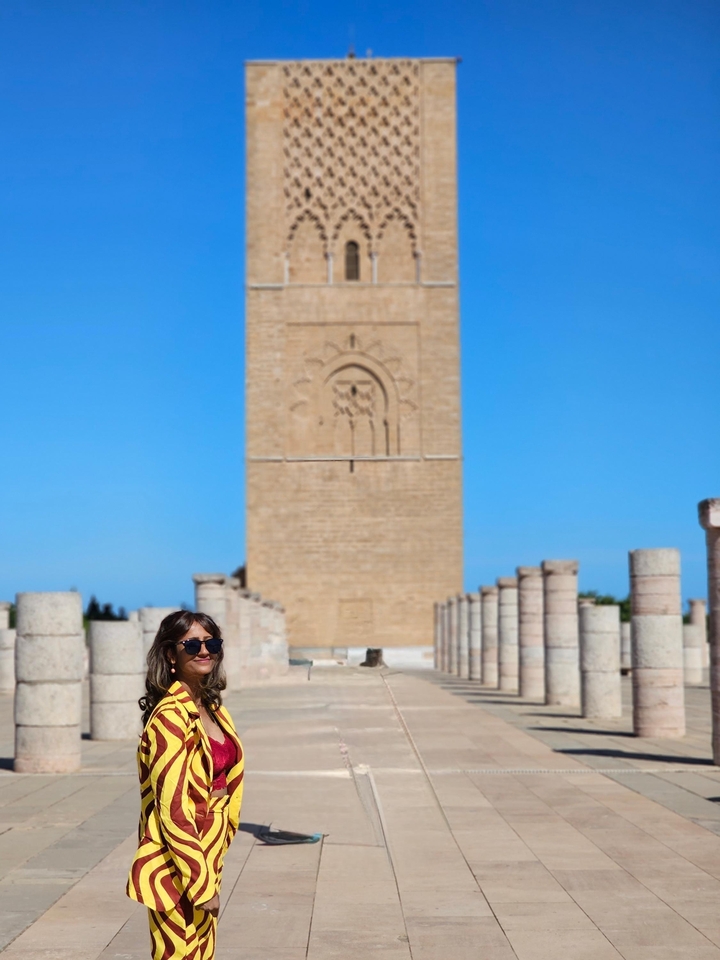 Femme debout devant une ruine antique à colonnes.
