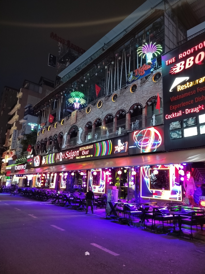 Façade vibrante de restaurant et bar illuminée la nuit avec des néons.