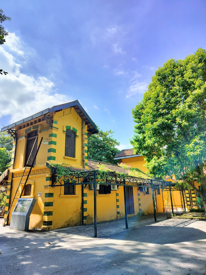 Bâtiment de style colonial aux couleurs vives entouré d'arbres.