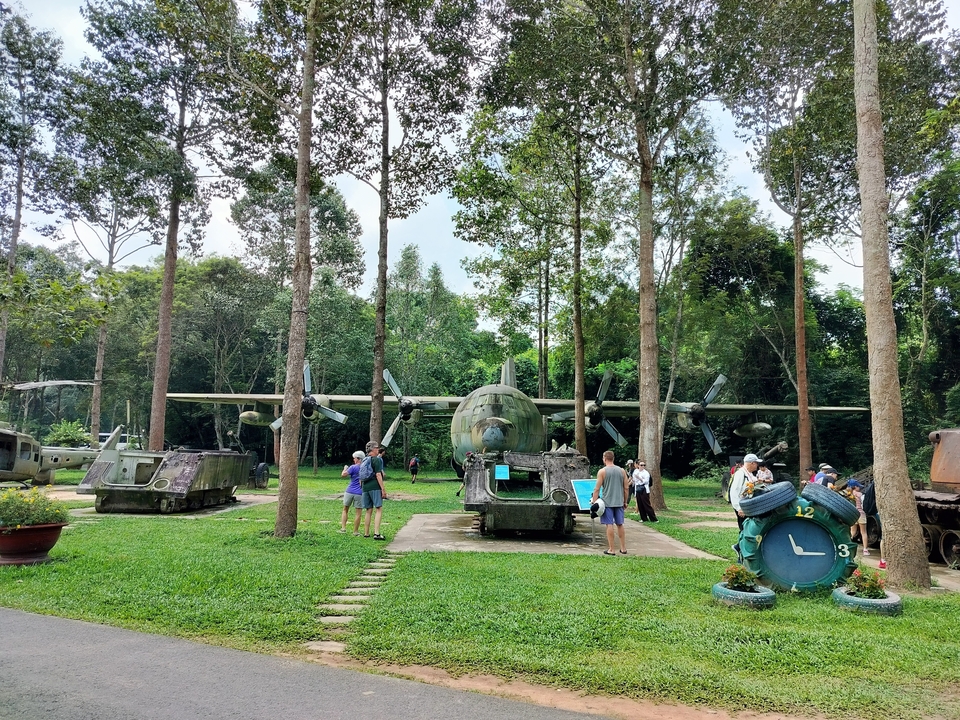 Exposition de musée militaire en plein air avec des avions et des chars dans une zone boisée.