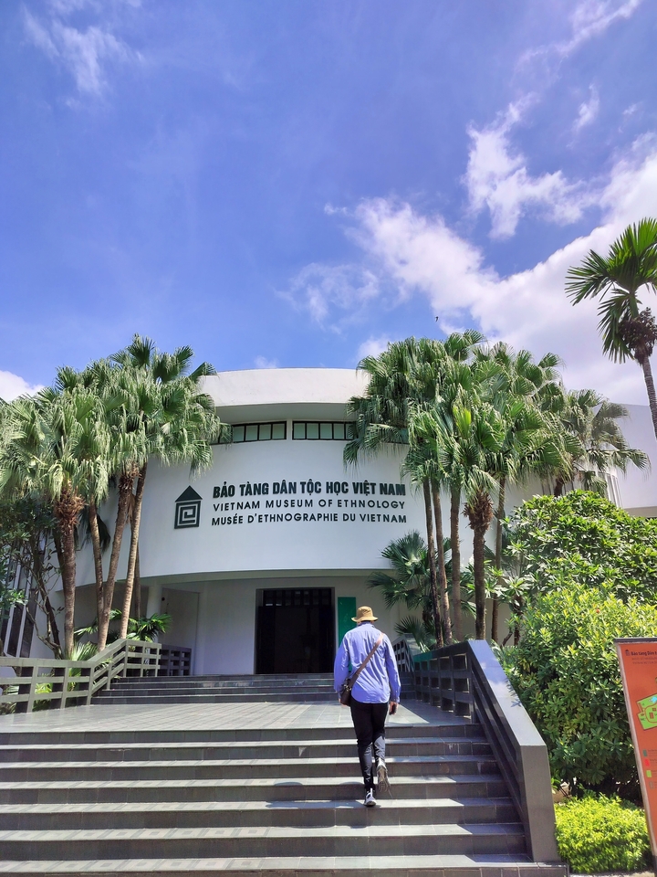 Musée ethnographique avec palmiers et une entrée incurvée.