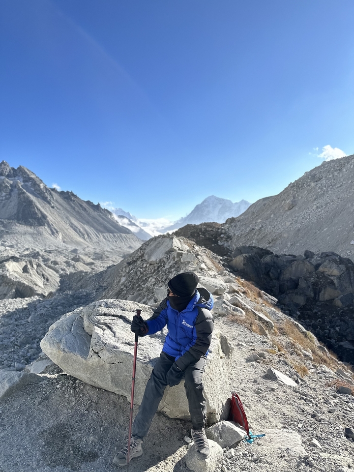 Randonneur faisant un pouce levé dans un paysage rocheux de l'Himalaya.