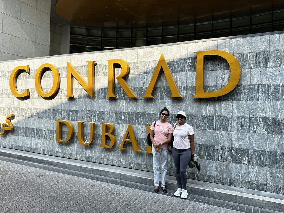 Deux personnes posant devant un panneau d'hôtel.