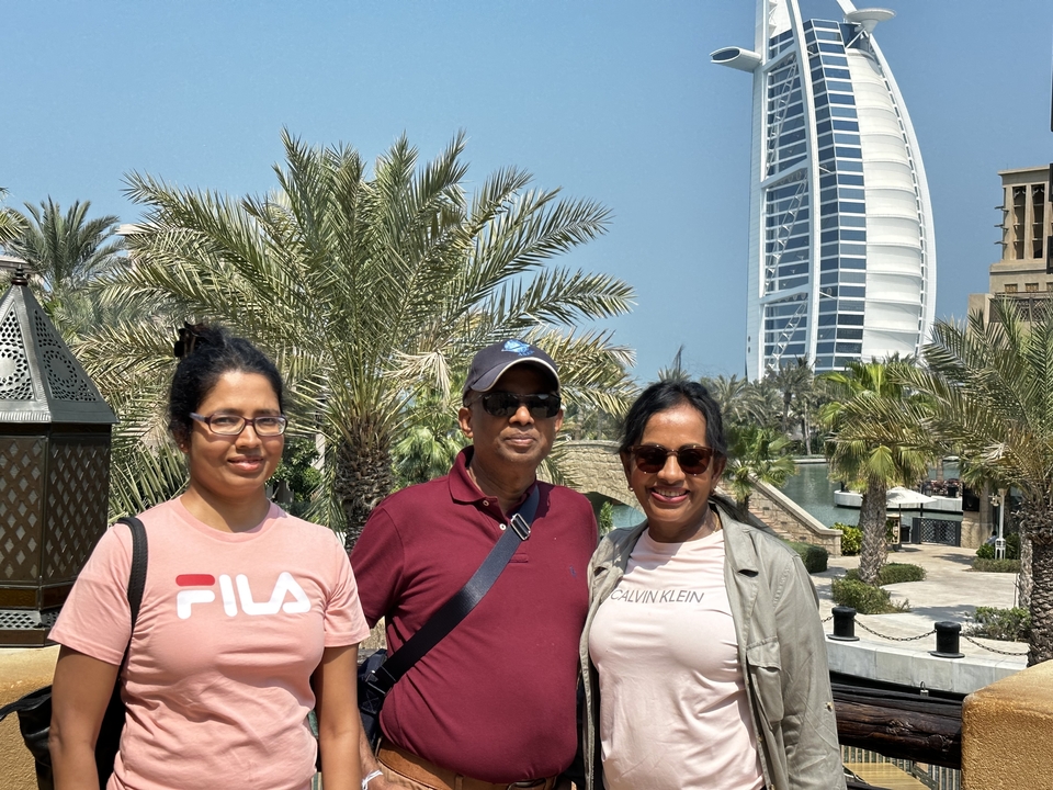 Famille posant dans un espace jardin avec un grand bâtiment en arrière-plan.