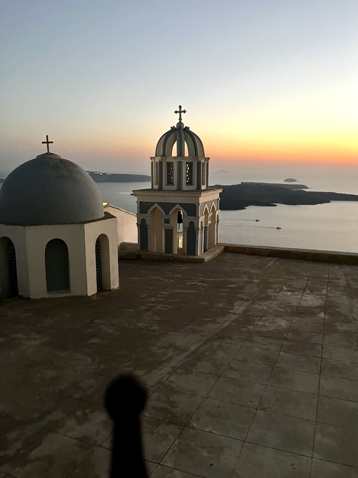 Vue panoramique d'un dôme d'église et de la mer au coucher du soleil.