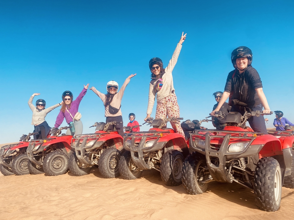 Groupe de femmes sur des quads prenant la pose dans le désert.