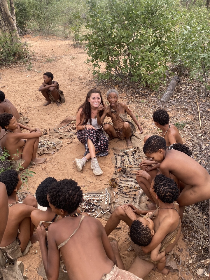 Groupe de personnes assises sur le sable avec de l'artisanat traditionnel.