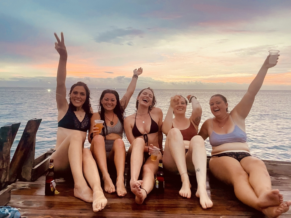 Groupe de femmes savourant des boissons au bord de l'eau au coucher du soleil.