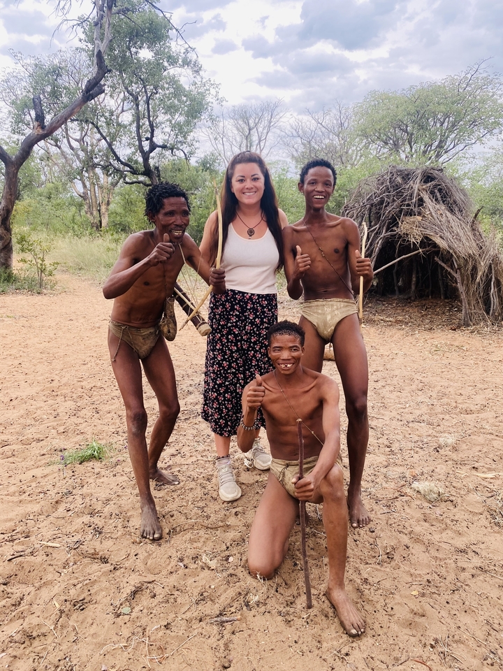 Quatre personnes posant avec des arcs et des flèches traditionnels.