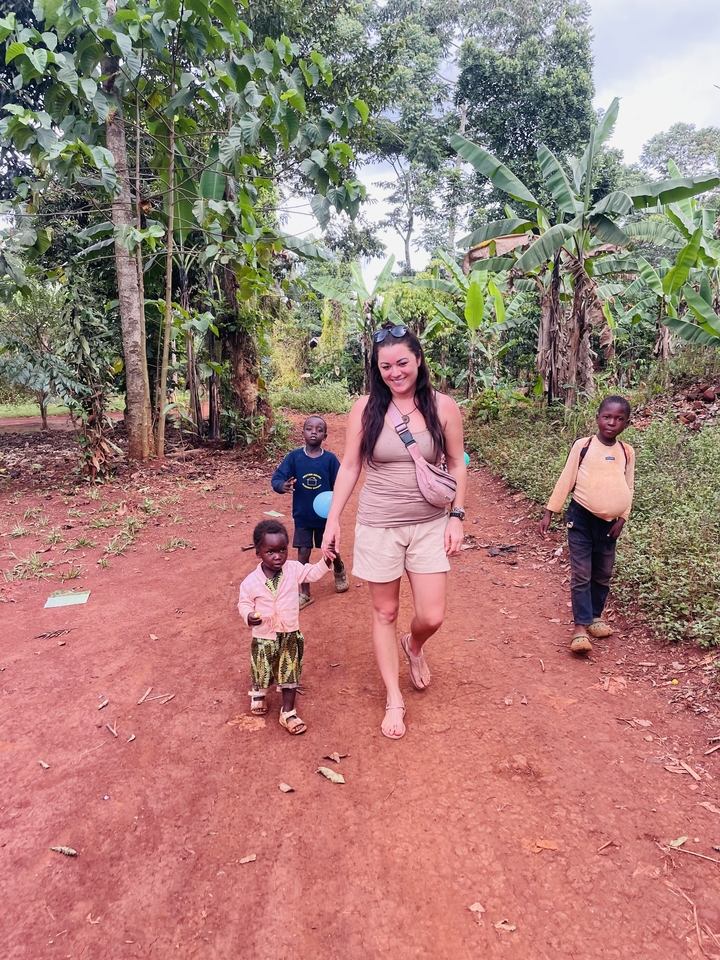 Femme marchant avec des enfants du coin sur un sentier de terre.