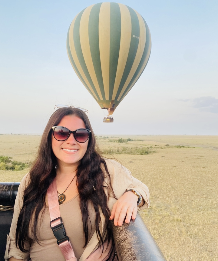 Personne posant devant une montgolfière dans le ciel.