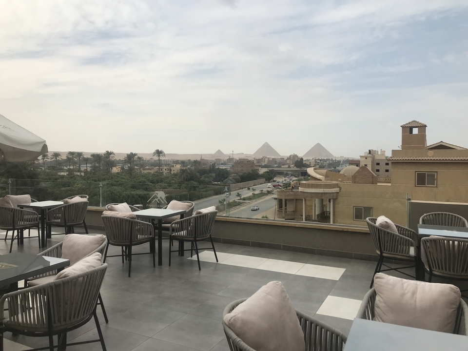 Vue des pyramides depuis une terrasse sur le toit avec des sièges extérieurs.