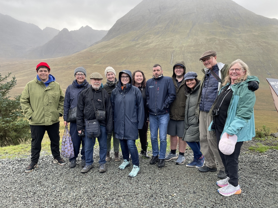 Groupe de personnes debout devant un paysage de montagne.