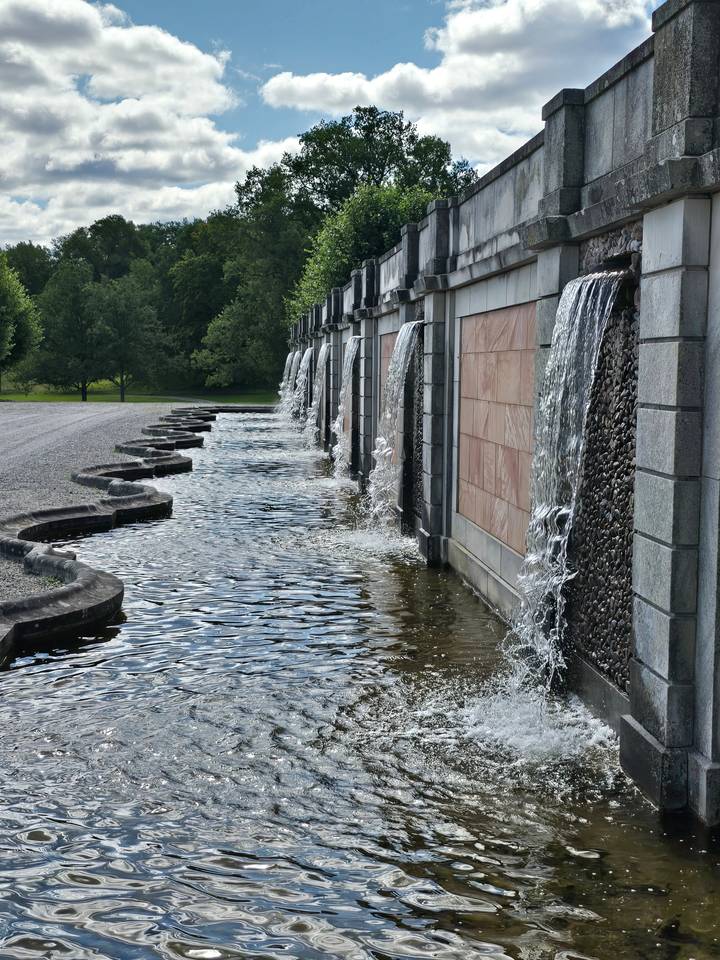 Des jeux d'eau qui cascadent le long de marches avec des arbres en arrière-plan.