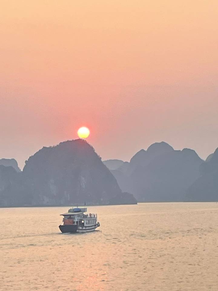 Coucher de soleil sur l'océan avec la silhouette d'un bateau.
