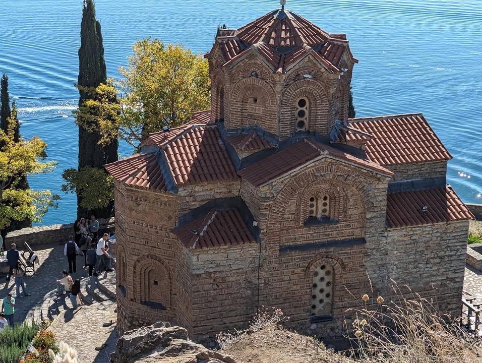 Église historique à dôme au bord de l'eau avec des touristes à proximité.