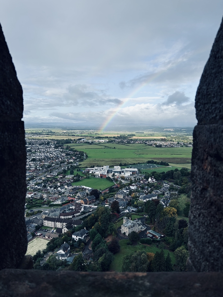 Une vue pittoresque de la campagne avec un arc-en-ciel vu depuis une fenêtre de château.