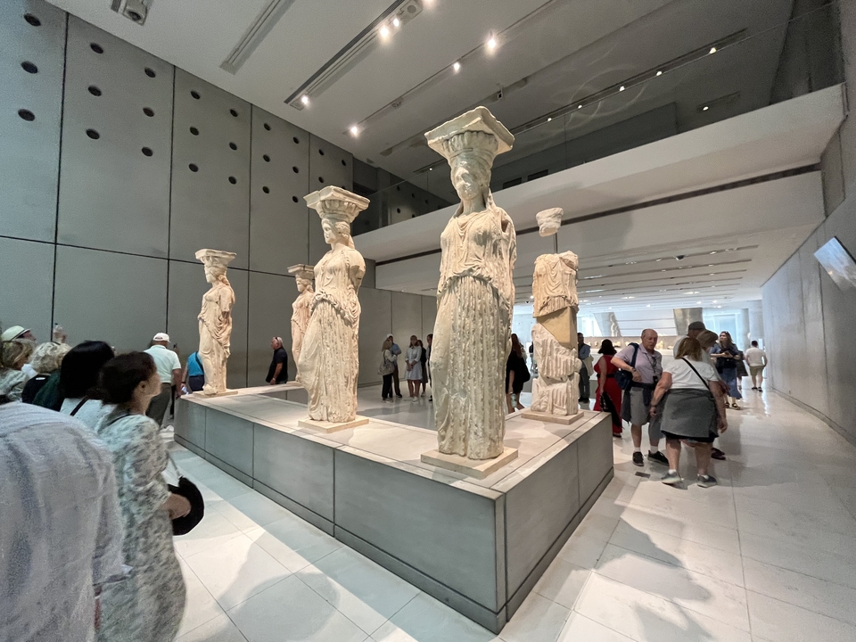 À l'intérieur d'un musée avec des sculptures antiques et des visiteurs.