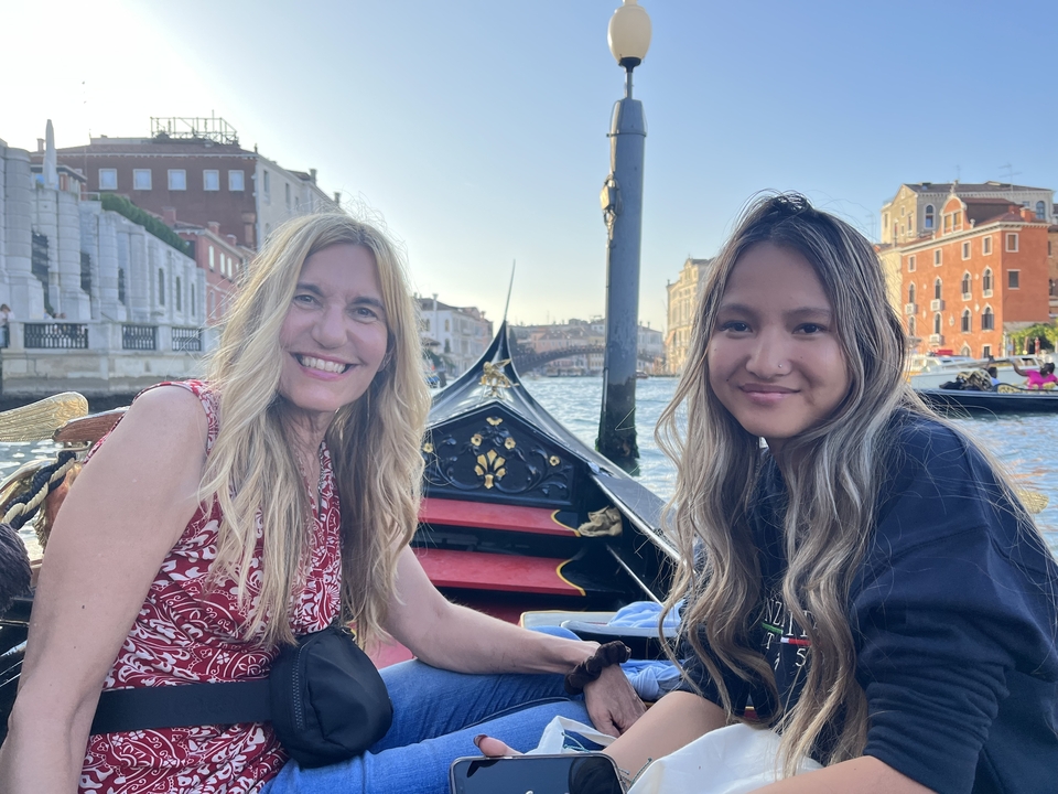 Deux femmes sur un bateau à Venise avec des bâtiments bordant le canal.