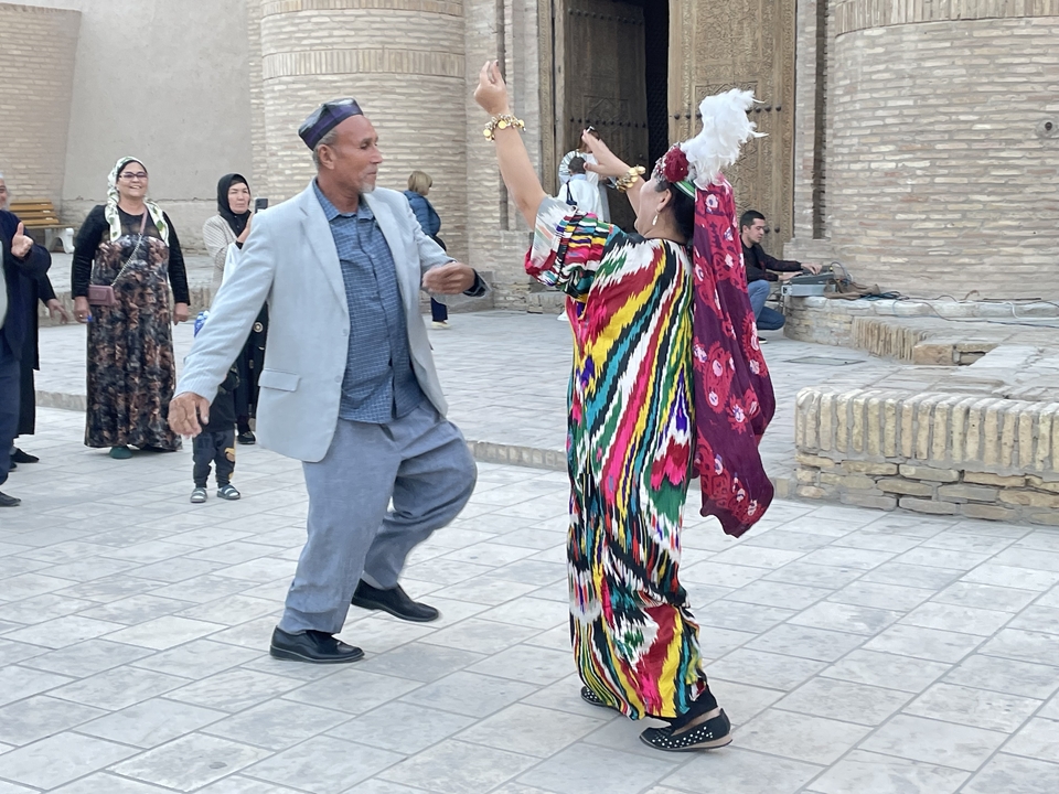 Personas bailando con vestimenta tradicional dentro de un sitio histórico.