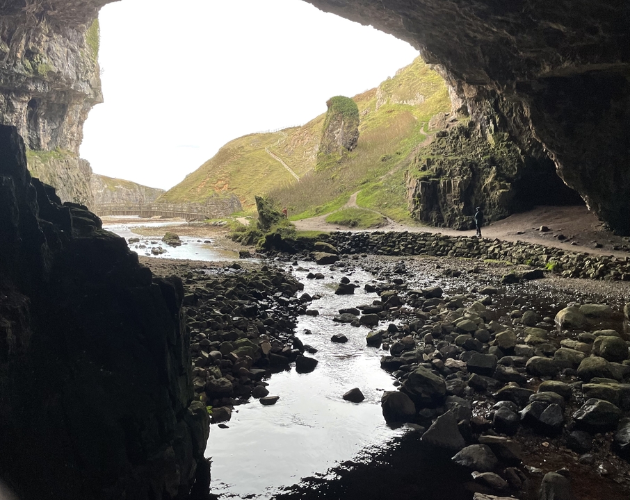 Entrée de grotte avec un ruisseau qui la traverse.