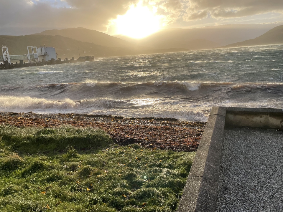 Vagues côtières se brisant près d'un port au coucher du soleil.