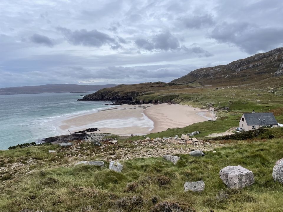 Plage de sable avec des collines ondulantes en arrière-plan.