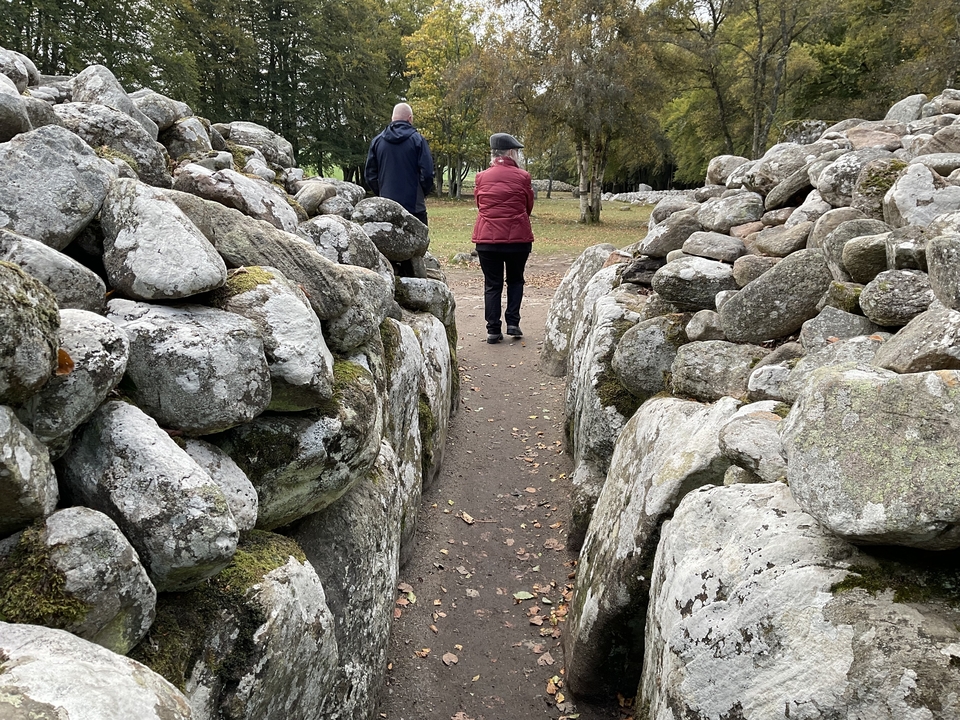 Des gens qui marchent dans un passage en pierre entouré de rochers.