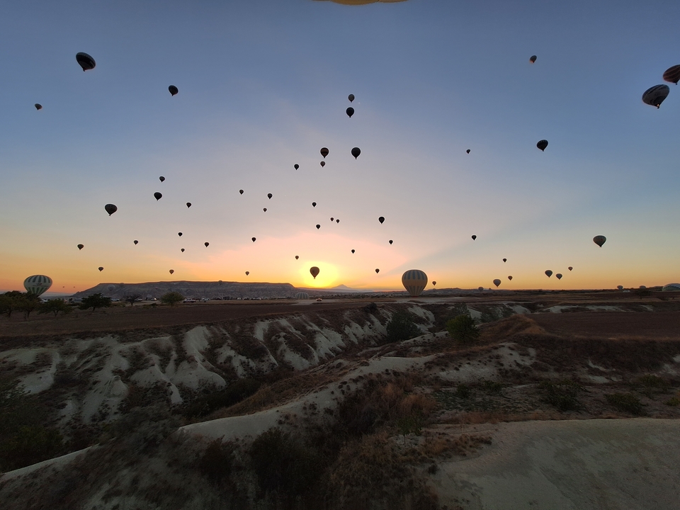 Montgolfières flottant au-dessus d'un paysage au lever du soleil.