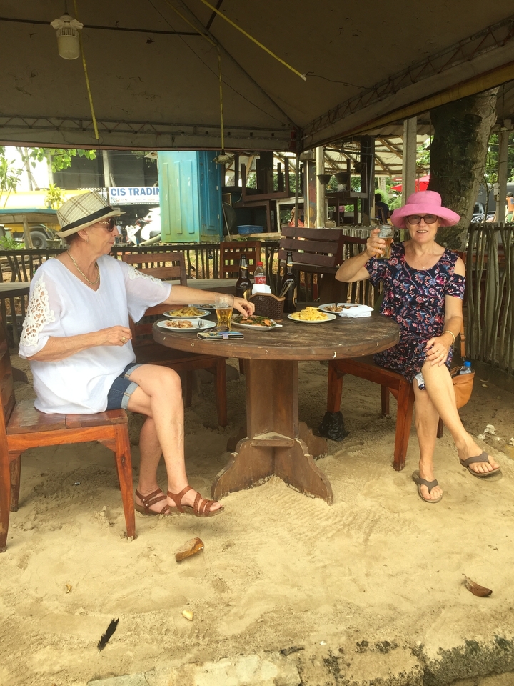 Deux femmes assises à une table avec de la nourriture et des boissons.
