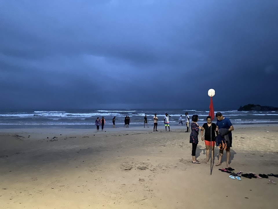 Des gens se sont rassemblés sur une plage au crépuscule.