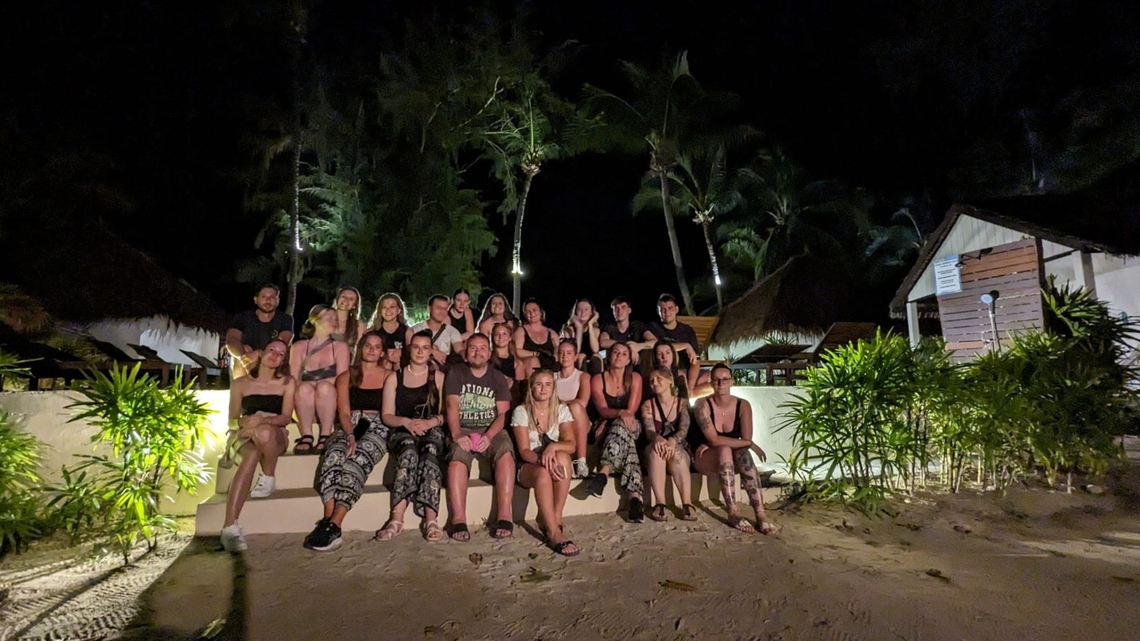 Grupo de personas posando por la noche en una zona arenosa.