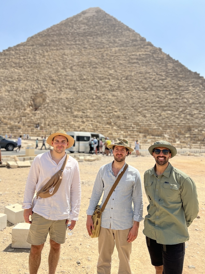 Trois hommes devant les pyramides sur un site archéologique.