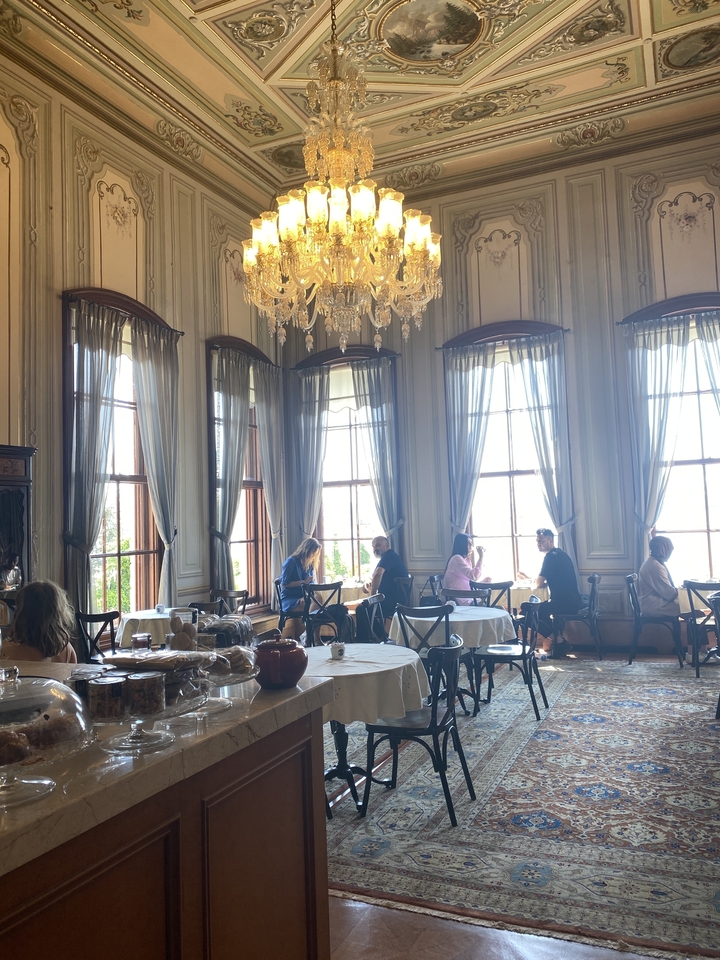 Intérieur d'un café historique avec des personnes assises près de grandes fenêtres.