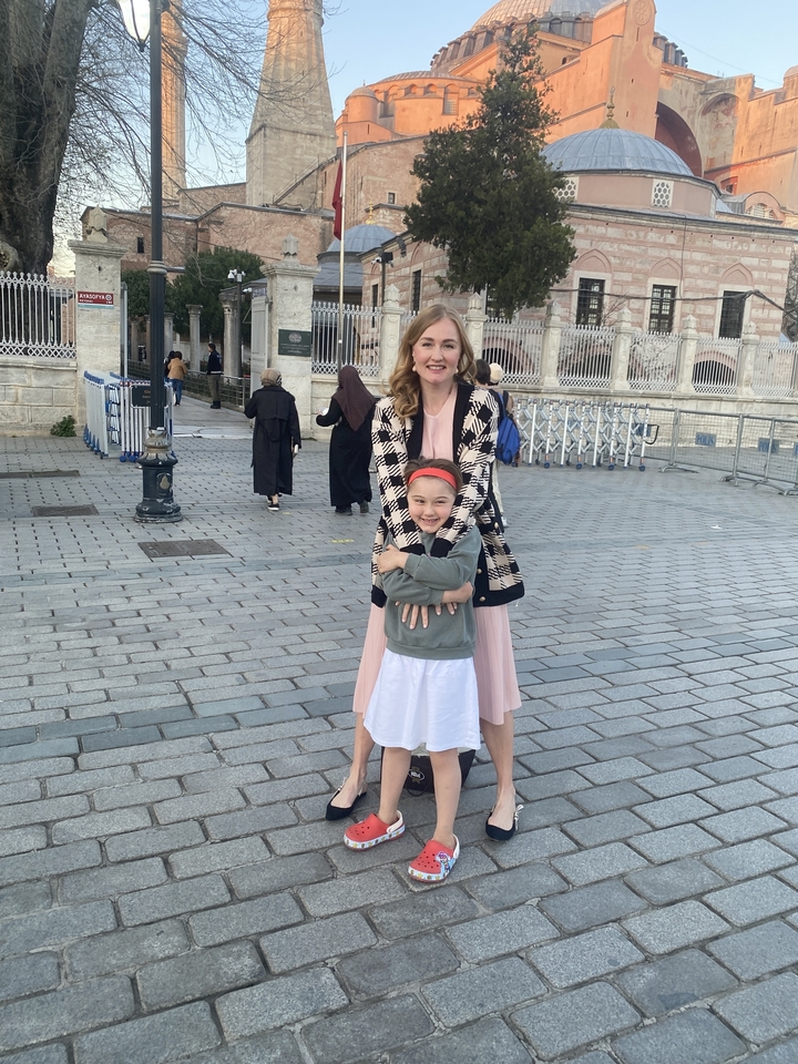 Mère et enfant posant joyeusement dans une rue urbaine pavée.