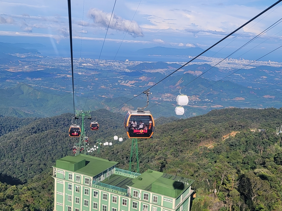Téléphériques passant au-dessus des montagnes avec vue sur la ville.