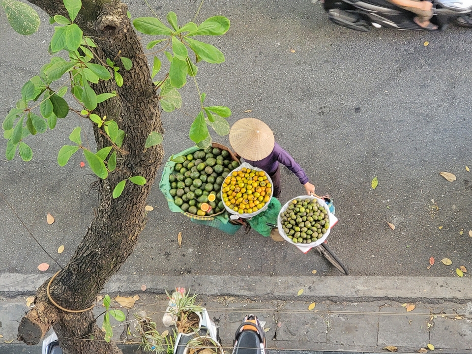 Vendeur portant des paniers de fruits.