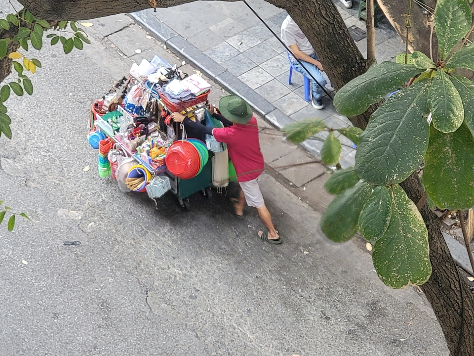 Vendeur ambulant poussant une charrette pleine de marchandises.