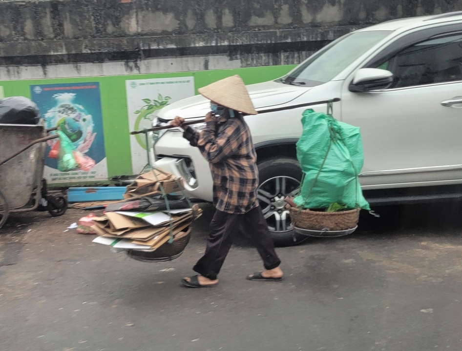 Vendeur ambulant portant des marchandises sur une perche.