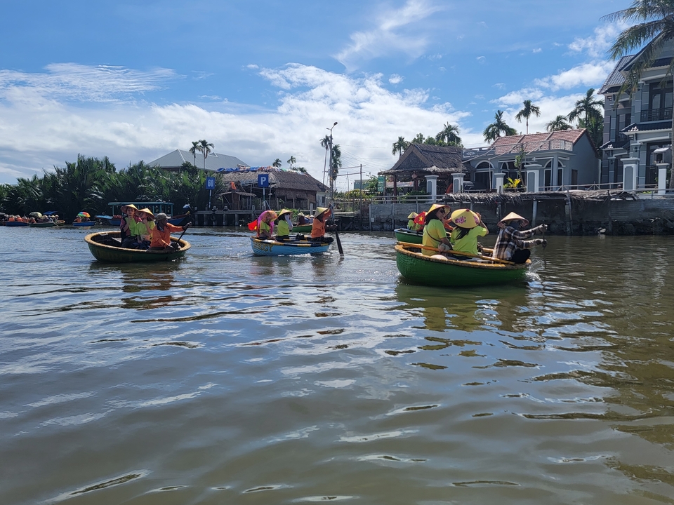 Groupe de personnes dans des bateaux traditionnels sur une rivière.
