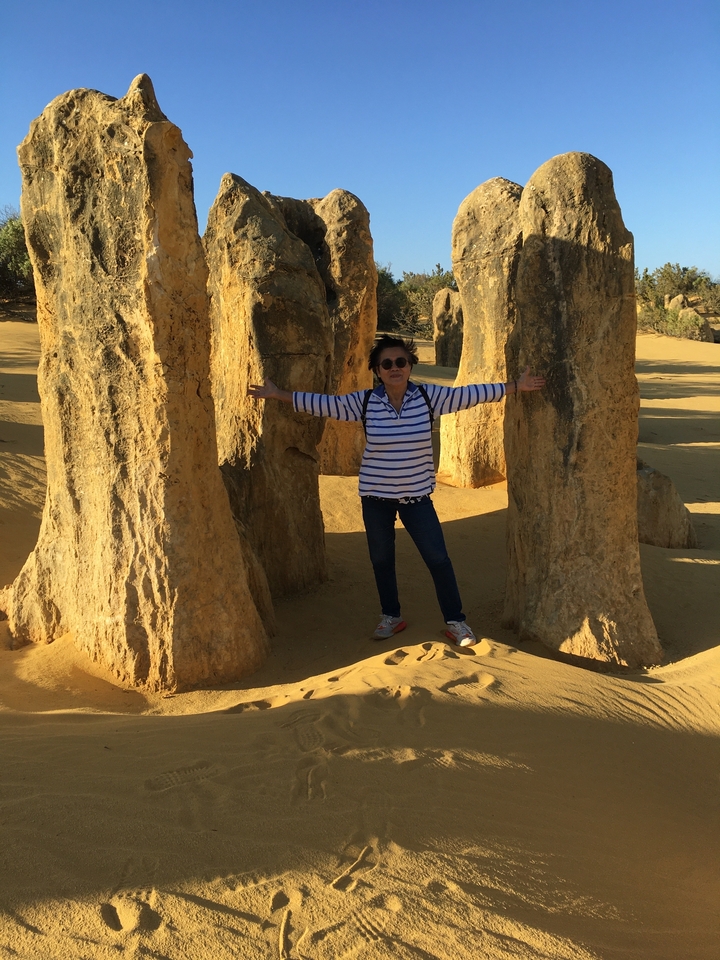 Personne posant avec des formations calcaires dans le désert.