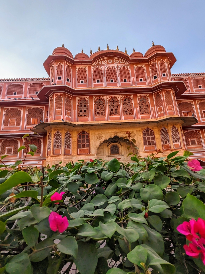 Façade ornée du Palais de la Ville à Jaipur entourée de feuillage.