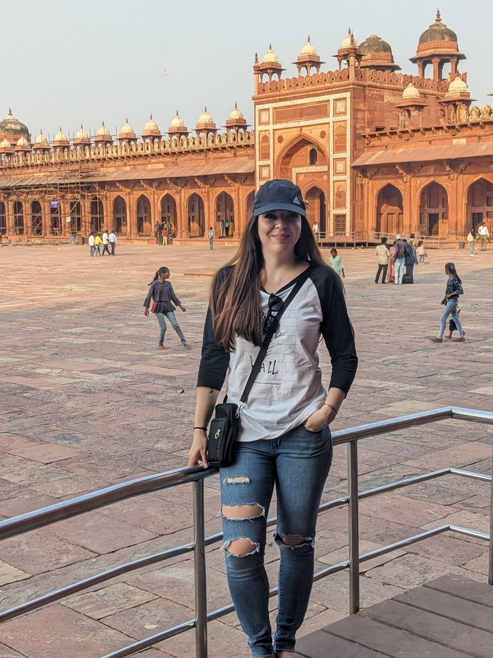 Femme posant sur un site historique avec d'autres visiteurs visibles.