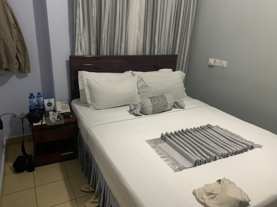 Lit de chambre d'hôtel avec du linge de lit blanc et un téléphone sur la table de nuit.