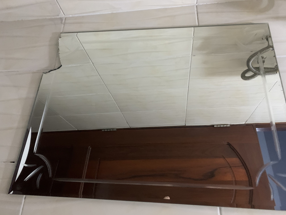 Miroir de salle de bain fissuré reflétant le plafond.