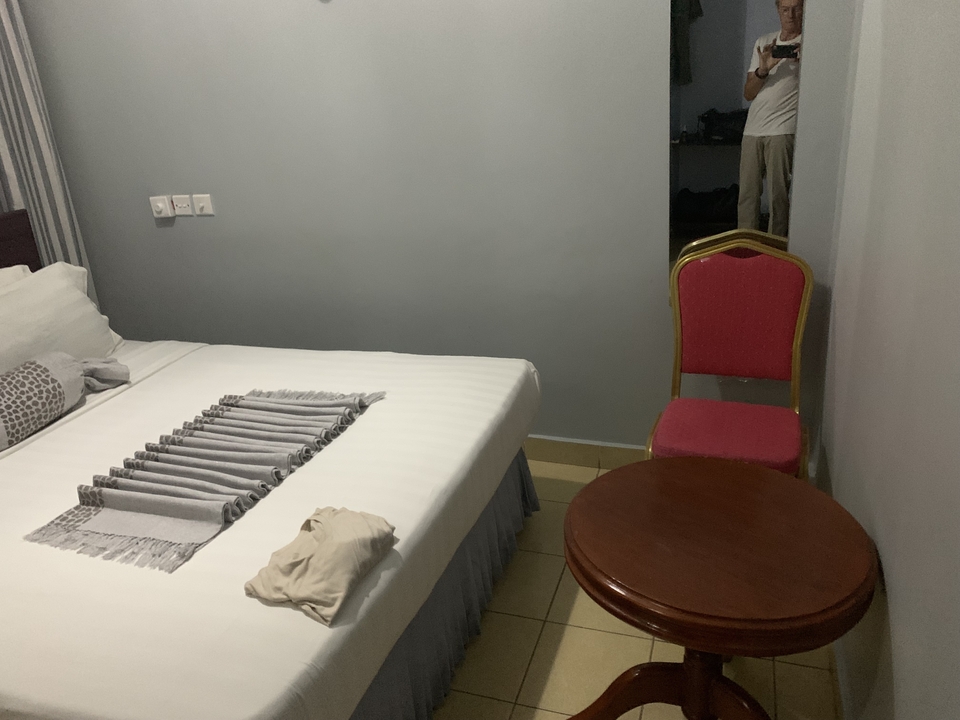 Chambre d'hôtel simple avec un lit, une chaise et une petite table.