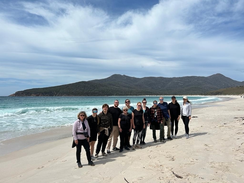 Photo de groupe sur une plage de sable avec des collines en arrière-plan.