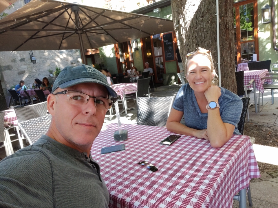 Couple assis à une table de café en plein air avec une nappe à carreaux rouges.