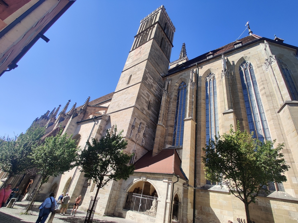 Église historique avec de hautes fenêtres en vitraux et des arbres au premier plan.